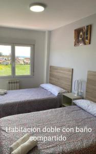 1 dormitorio con 2 camas y ventana en Pension Ameneiral, en O Pedrouzo