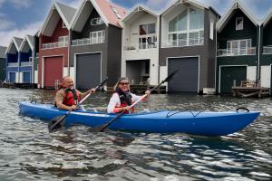 two people kayaking on the water in front of houses at Nomad Water Lodge in Harderwijk