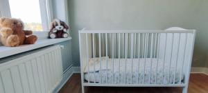 a white crib in a room with two stuffed animals at Kind -& diervriendelijk huisje in De Panne