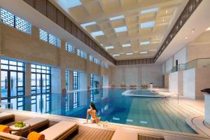 una donna seduta sul bordo di una piscina di Angsana Xi'an Lintong a Lintong