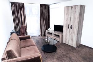 HOF HOTEL في كاوناس: غرفة معيشة بها أريكة وتلفزيون