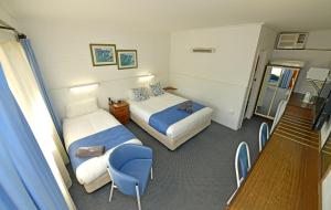 una habitación de hotel con 2 camas y una silla azul en Sturt Motel Balranald en Balranald