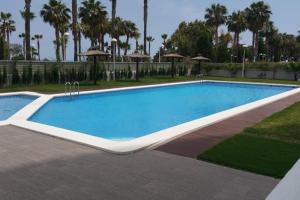 uma grande piscina num resort com palmeiras em Edificio Mondrian 1ª Linea vistas al mar em Oropesa del Mar