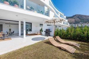 a house with two lounge chairs and an umbrella at 797 HOLIDAY RENTALS - Lujoso apartamento para 6 con jacuzzi en Higueron in Málaga