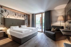 a hotel room with a large bed and a chair at Hotel Christof in Monguelfo