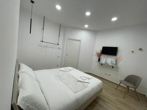 a white bedroom with a bed and a chair at All'Uscita B&b in Eboli