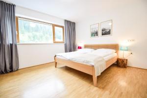 a bedroom with a bed and a large window at Toferer Textil in Eben im Pongau