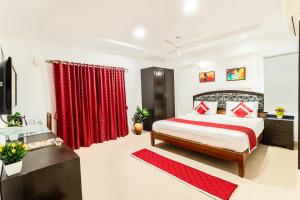 1 dormitorio con 1 cama grande y cortinas rojas en Octave Fairmont Suites, en Bangalore