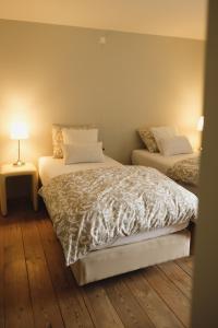 In De Witte Engel في لاناكن: غرفة نوم بسريرين ومصباح على أرضية خشبية