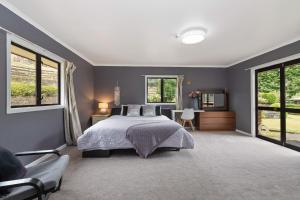 1 dormitorio con 1 cama grande y ventanas en skyline mountain view Lodge up to 16 people en Rotorua