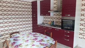 cocina con mesa y cocina con armarios rojos en La Casa di Rocchina, en Sora