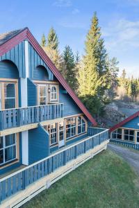 a blue house with a balcony and trees at Bakkebyvegen 20A in Trysil