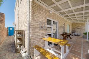 a patio with a wooden table on a brick wall at Colours of the Sea Apartment in Struisbaai