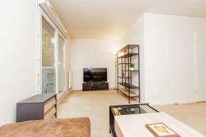 een woonkamer met een groot raam en een televisie bij Bright 68 m2 apartment near the Stade de France in Aubervilliers