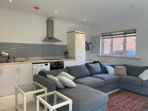 a living room with a blue couch and a kitchen at Fully Detached Studio Annexe with Double Bed for 2 & Sofa Bed for 2 in Cambourne