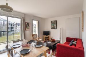 - un salon avec une table et un canapé rouge dans l'établissement Le Bienveillant - T3 proche Jardin des Plantes, à Nantes