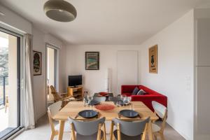 - une salle à manger avec une table, des chaises et un canapé rouge dans l'établissement Le Bienveillant - T3 proche Jardin des Plantes, à Nantes