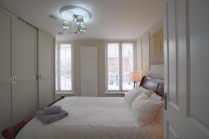 Harper Luxe Serviced Apartments Dunstable في دانستابل: غرفة نوم بسرير وملاءات بيضاء ونوافذ