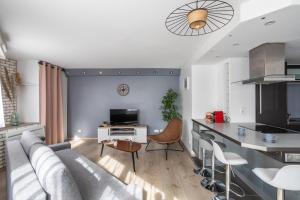 salon z szarą kanapą i kuchnią w obiekcie Le Crucy - T2 avec Parking w mieście Nantes