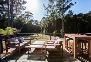 un patio con un tavolo e sedie in legno e un tavolo e un tavolo e sedie di Bush and Beach Family Retreat ad Adventure Bay