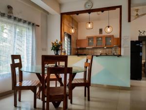 a dining room with a table and chairs and a kitchen at Mel Ville in Pondicherry