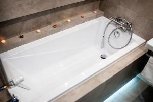 uma banheira branca com um chuveiro na casa de banho em Apartament Południowy W80 em Żory