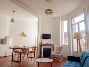 a living room with a fireplace and a table and chairs at Le CosyChic - Appartement élégant en centre ville in Orange