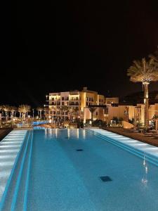 - une grande piscine dans un complexe la nuit dans l'établissement Address Beach Resort Residence Fujairah, à Fujaïrah