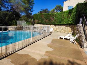 una valla alrededor de una piscina con dos sillas al lado en Villa plein soleil, en Valbonne
