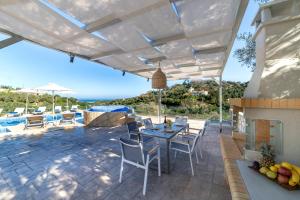 a patio with a table and chairs and an umbrella at Etesians Villa, an essence of timeless beauty, By ThinkVilla in  Episkopi (Chania)