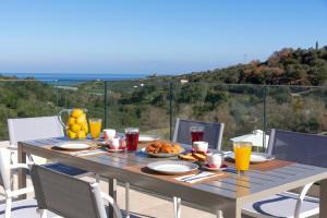 a table with food and drinks on a balcony at Etesians Villa, an essence of timeless beauty, By ThinkVilla in  Episkopi (Chania)