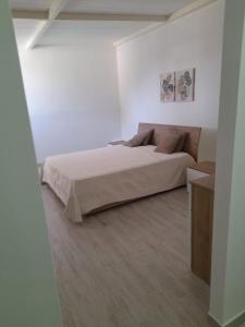 um quarto branco com uma cama e piso em madeira em House Garden Adim em Brucoli