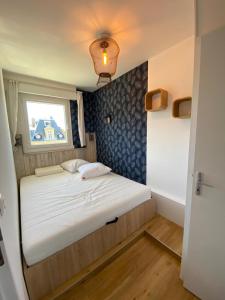 een klein bed in een kleine kamer met een raam bij Les Pins Penchés in Villers-sur-Mer