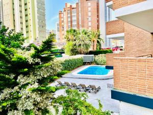 a view of a building with a pool and chairs at Trebol One Apartments By Mc in Benidorm