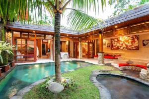 een huis met een zwembad en een palmboom bij Nidhi Private Villas in Ubud