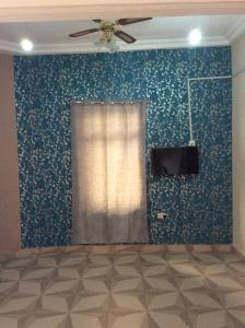 a room with a blue wall with a ceiling fan at Patayo Lodge in Kumasi