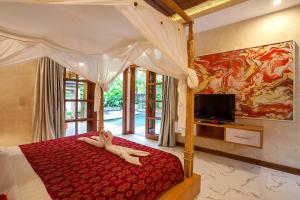 een slaapkamer met een bed met een rood dekbed en een tv bij Nidhi Private Villas in Ubud