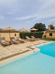 een zwembad met ligstoelen en parasols bij Cal Colina - Karaktervol landhuis met privé zwembad in Pacs del Penedes