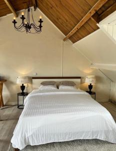 a bedroom with a large white bed with two lamps at Maison Blakenburg in Wissenkerke