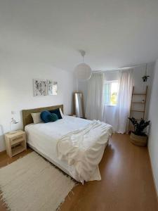 - une chambre avec un grand lit blanc et un tapis dans l'établissement Casa da Boa Gente, à Cabanas de Tavira