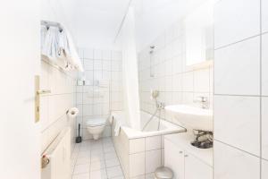a white bathroom with a toilet and a sink at Boardinghouse St.Pauli in Hamburg