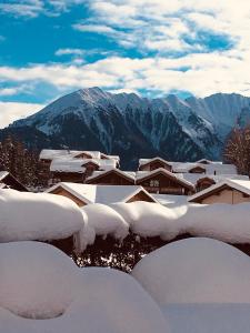 a bunch of snow covered buildings with mountains in the background at Laax Cozy Apartment Ski Bus in front of the Door in Laax