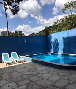 uma piscina com duas cadeiras e uma cerca azul em Pousada Trilha do Sol em Pirenópolis