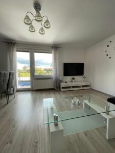 uma sala de estar com uma mesa de vidro e uma televisão em Apartament NAD CZEREŚNIĄ em Brodnica