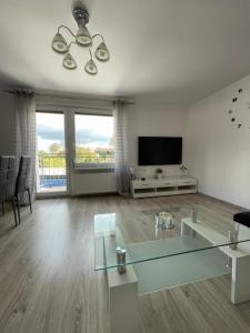 a living room with a glass table and a television at Apartament NAD CZEREŚNIĄ in Brodnica