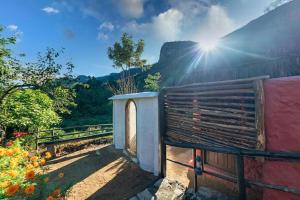 a building with the sun shining on a mountain at Deshadan Eco Valley Resort - An Eco friendly Mud House in Kanthalloor