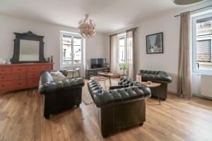 a living room with leather furniture and a chandelier at Grande Maison Vichy - Maison ou Appartements en Centre ville in Vichy