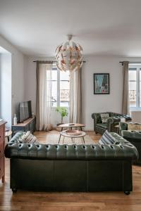 a living room with a black leather couch at Grande Maison Vichy - Maison ou Appartements en Centre ville in Vichy