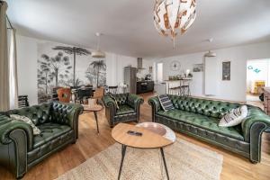 a living room with green leather couches and a table at Grande Maison Vichy - Maison ou Appartements en Centre ville in Vichy