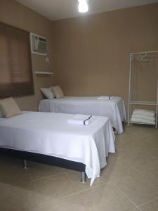 2 camas en una habitación de hospital con sábanas blancas en ReCanto dos Passáros - Guaratiba, en Pedra de Guaratiba